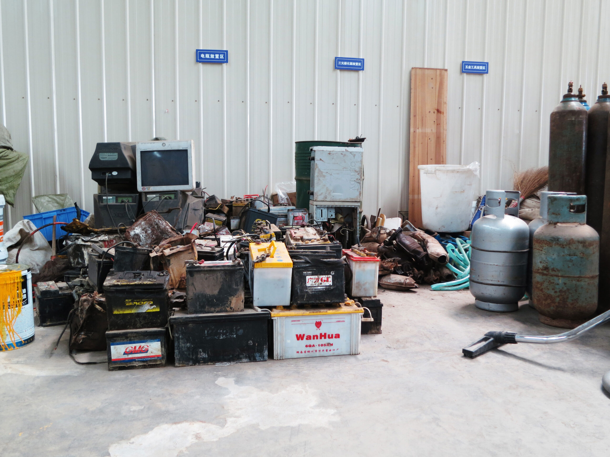 Computer waste, propane fuel tanks, and assorted containers arranged into neat piles.