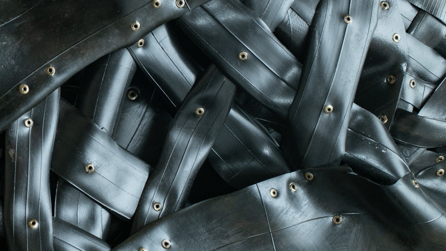 A pile of black rubber sheets and tubing with randomly placed grommets