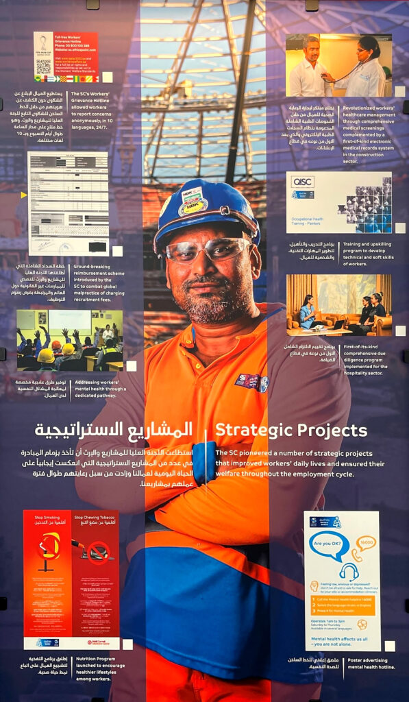 Exhibit panel featuring a smiling migrant construction worker at the National Library of Qatar, 2024.